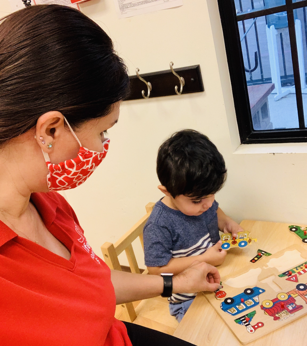 Toddler playing with puzzles while Montessori Teacher provides guidance