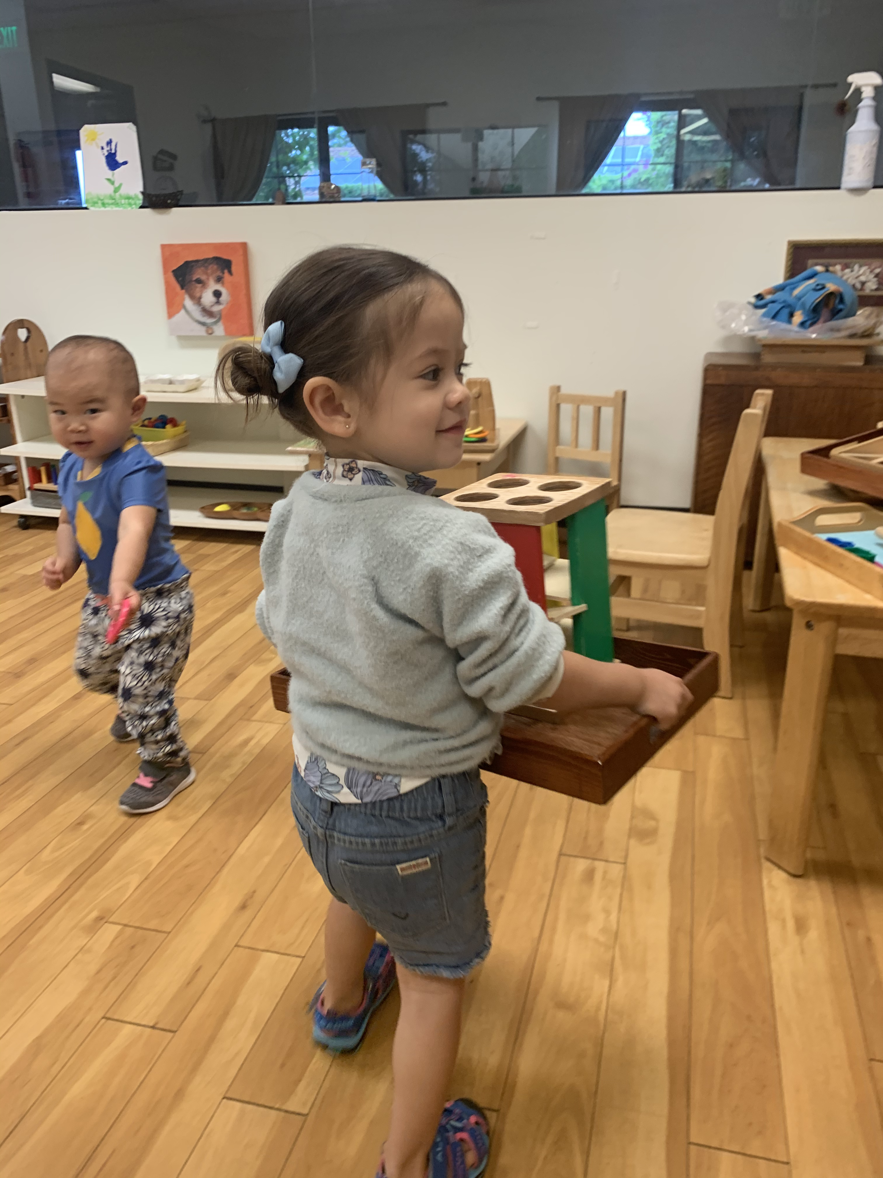 Toddler carrying her tray of activities she independently chose in a Montessori classroom