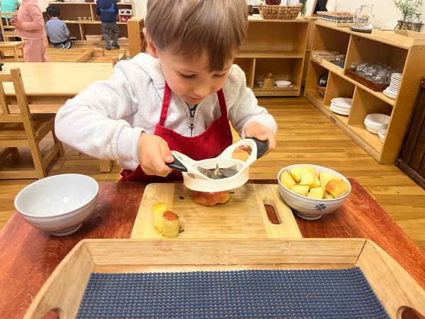 Child slicing apples for snack time Practical Life Into Play at Lifetime Montessori School San Diego