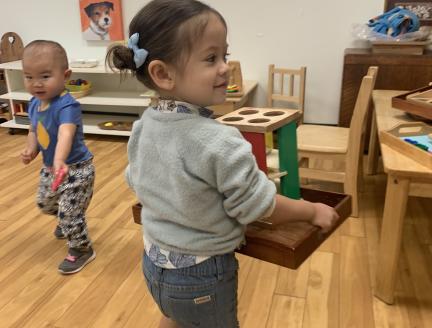 Toddler carrying her tray of activities she independently chose in a Montessori classroom