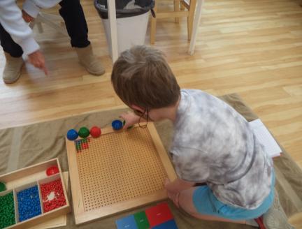 Boy Learning math in a Montessori Classroom with Teacher guidance