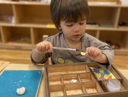 Preschooler in a Montessori classroom gluing with a paint brush