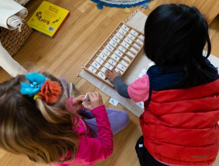 Boy and girl socializing while learning to spell in their Montessori classroom