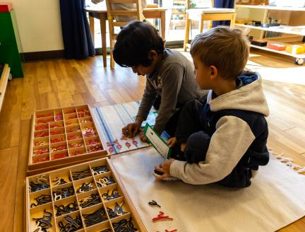 Two Boys using cursive letters to write in Montessori Classroom