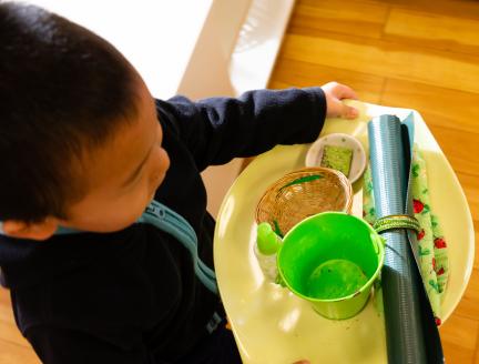 Boy carrying his plate sitting in a Montessori classroom