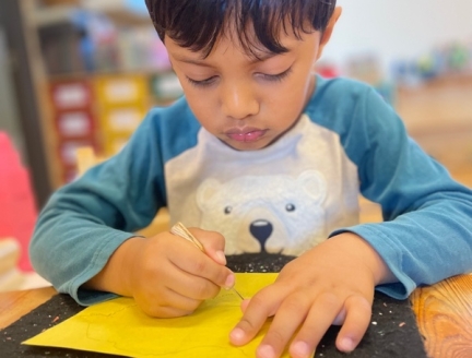 A Primary child concentrating and being observed in his Montessori Classroom in San Diego