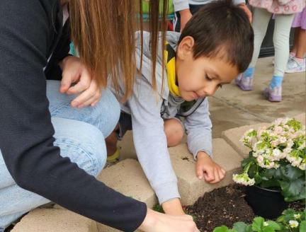 Child Exploring the World Through Language with teacher in the garden