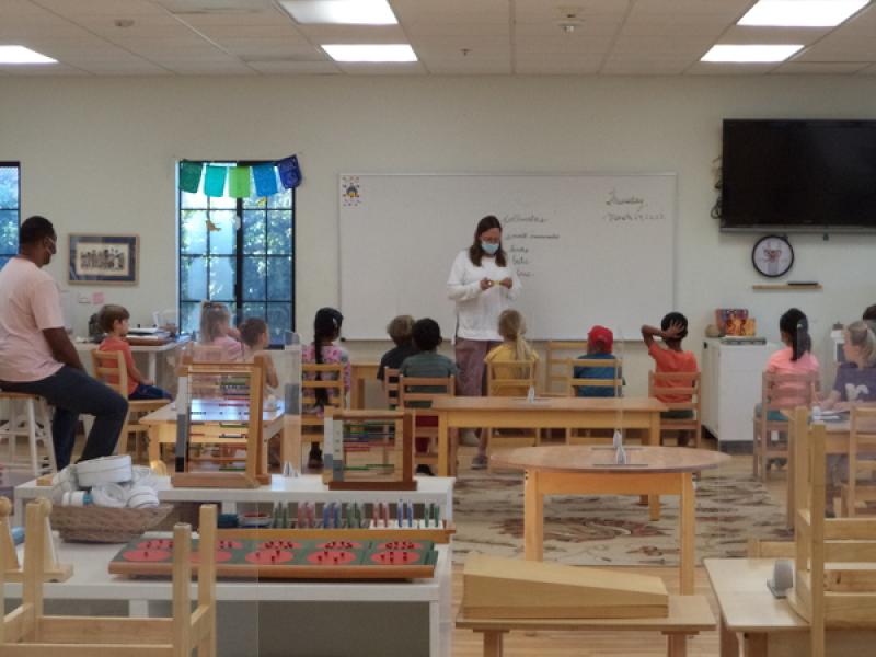 Montessori Teacher noticing the classwork children are working on