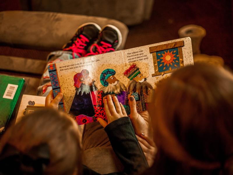 Mother and child reading a book together on the couch