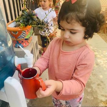 Toddler independently gardening and pouring water from a spout at Lifetime Montessori School 