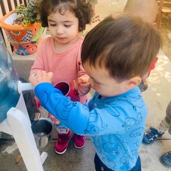 Toddler independently gardening and pouring water from a spout at Lifetime Montessori School 