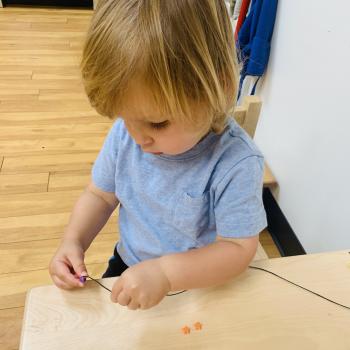 Toddler independently learning how to sew at Lifetime Montessori School 