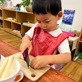 Toddler independently cutting slices of cheese at Lifetime Montessori School 