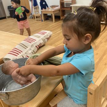 Toddler independently cleaning doll at Lifetime Montessori School 