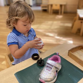 Toddler independently cleaning shoe after playtime at Lifetime Montessori School 