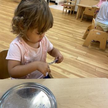 Toddler independently cutting with scissors at Lifetime Montessori School 
