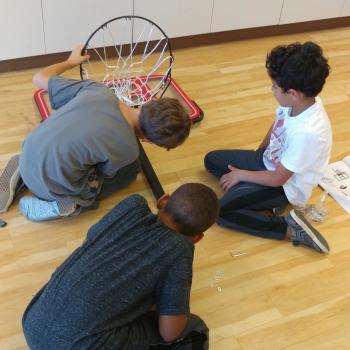 Elementary boys fixing a basketball net